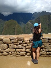 Naklejka premium Girl photographing - Machu Picchu - The lost city of the Inca in Peru, South America. Set high in the Andes Mountains, is a UNESCO World Heritage Site and one of the New Seven Wonders of the World.