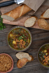Beet greens and potato soup with bread and crispy onion, wooden background