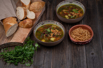 Beet greens and potato soup with bread and crispy onion, wooden background
