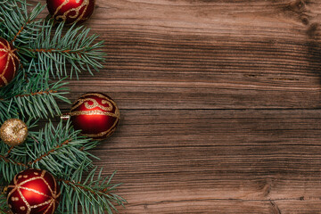 Frame made of Christmas tree branches  with red and gold  balls on a dark wooden background.New Year,Christmas concept. Copy space for text,top view, selective focus with shallow depth of field