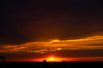 Heavy cloudy sky at sunset. Orange line of light between black clouds. A landscape of beautiful nature