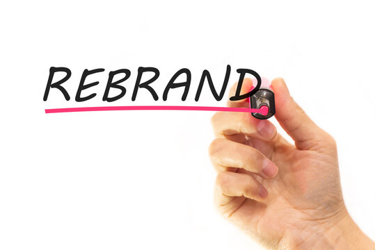 the hand writes the word rebrand with a marker on a white background. business concept