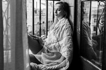 happy young girl. Morning sunrise girl sitting on the balcony wrapped in a bright blanket, nice morning. Selective focus. Black and white photo 