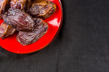 Big luxury dried date fruit in bowls on the dark surface, kurma ramadan kareem concept, close up.