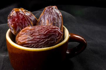 Big luxury dried date fruit in bowls on the dark surface, kurma ramadan kareem concept, close up.