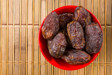 Big luxury dried date fruit in bowls on the bamboo mat, kurma ramadan kareem concept, close up.