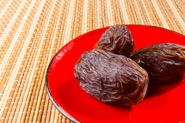 Big luxury dried date fruit in bowls on the bamboo mat, kurma ramadan kareem concept, close up.