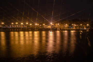 Night city view of the old bridge across the river lanterns six-pointed stars with water reflections