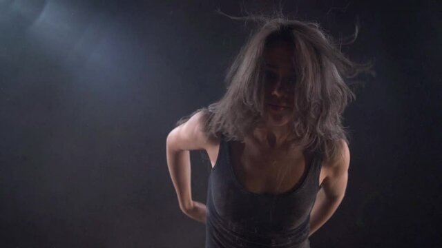 active and energetic dancer woman is moving in darkness, performing modern dance movements