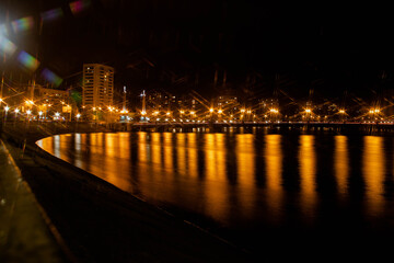 Night city view of the old bridge across the river lanterns six-pointed stars with smooth water reflections