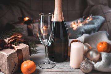 A bottle of champagne and a glass in a cozy Christmas atmosphere in the evening. Holiday background. The concept of New year and Christmas.