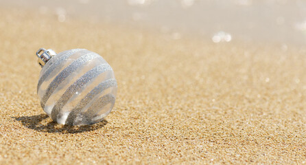 Christmas white glitter ball on the tropical beach near ocean, a summer Christmas and winter holyday concept. Merry Christmas and Happy New Year background,