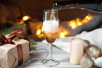 The process of filling a glass of champagne against the background of a cozy Christmas atmosphere. Holiday background. The concept of New year and Christmas.