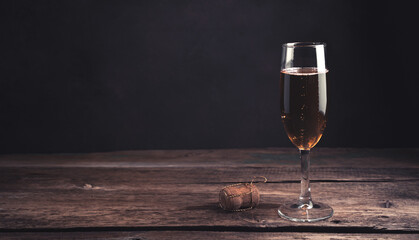 A glass of champagne on a dark wooden background. Panorama with space to copy. Concept of holiday backgrounds.