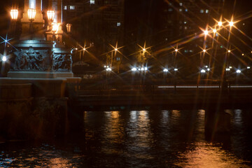 Night city view of the old bridge across the river lanterns six-pointed stars with water reflections