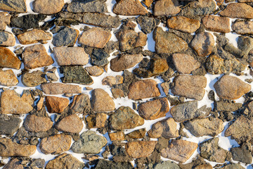 Old stone wall covered with snow. Weathered rough masonry surface. Texture for background and design.