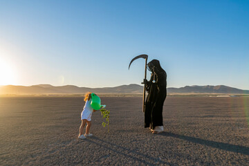 global climate change concept. horror grim reaper holding is holding a clock in one hand and a...