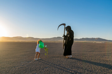 global climate change concept. horror grim reaper holding is holding a clock in one hand and a...