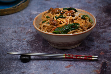 Korean kimchi and seitan fried noodles in bowl with chopsticks, copy space