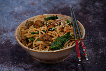 Korean kimchi and seitan fried noodles in bowl with chopsticks, copy space