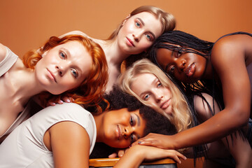 young pretty caucasian, afro, scandinavian woman posing cheerful together on brown background, lifestyle diverse nationality people concept