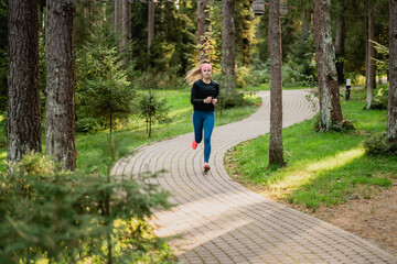 Obraz premium professionally engaged in running in the Park. portrait of a sporty female sports coach of Caucasian appearance brown-haired in comfortable clothes. aerobics training fitness training.