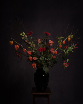 Studio still life of bouquet of autumn flowers in vase in classic dark Rembrandt style