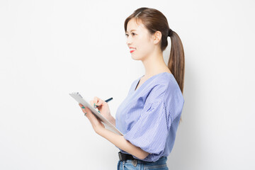 クリップボードにメモを書く若い女性