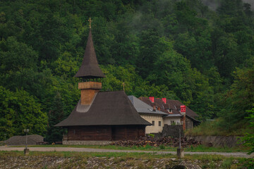 View of vodita monastery in Romania on a cloudy dull morning, monastery hiding in thick green forest.