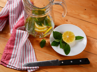preparation of lemonade, a decanter of water with mint and lemon slices, lemon and fresh mint on a...