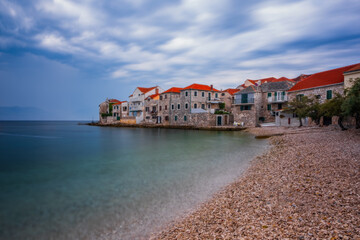 Fototapeta premium Traditional Dalmatian stone architecture, town Postira at sunset in august 2020. Long exposure picture. Beach Balatura, Brac island