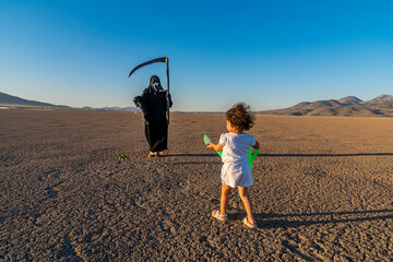 global climate change concept. horror grim reaper holding is holding a clock in one hand and a...