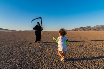 global climate change concept. horror grim reaper holding is holding a clock in one hand and a...
