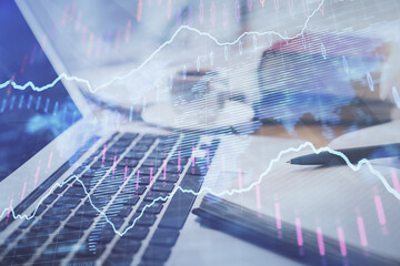 Double exposure of financial chart drawing and desktop with coffee and items on table background. Concept of forex market trading