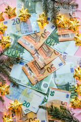 Small pile of paper euro bills and Christmas decoration on pink background. Christmas discounts. sales, business, investment, concept. Flat lay, top view, vertical image.