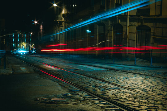 Empty street at night with with tram rails and long exposure light trails on traditional stone pavement road in Lisbon, Portugal. Film look effect, low key concepts