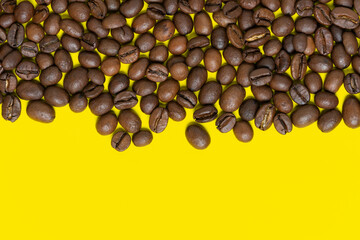 Brown coffee beans on bright yellow background. Top horizontal location objects, copy space for text at bottom. Flat lay, close-up view of colorful coffee still life.