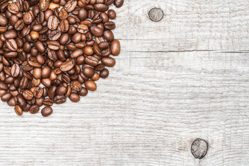 Brown coffee beans on light color wood background. Copy space. Close-up macro top view of still life.