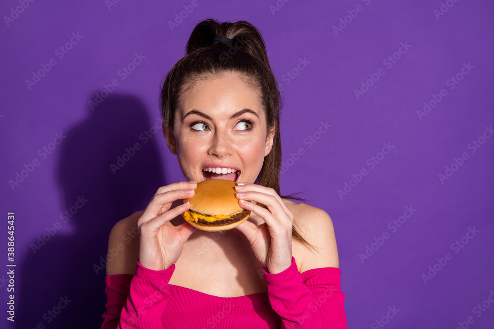 Wall mural close-up portrait of attractive cheerful girl eating fresh hot burger thinking copy space isolated o