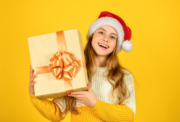 christmas shopping online. time for discount. smiling kid hold purchase. presents and gifts from santa claus. small girl santa at yellow background. xmas party celebration. happy new year