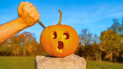 CLOS E UP: Halloween pumpkin with a shocked face is stabbed with a knife