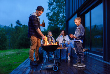 Happy father and son preparing a barbecue on a family vacation on the terrace of their modern house...