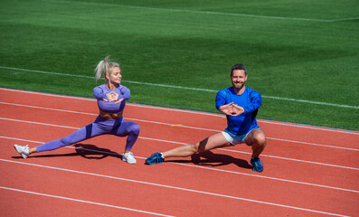 Fototapeta premium fitness sport couple warming up and stretching together on outdoor stadium racetrack wearing sportswear, workout