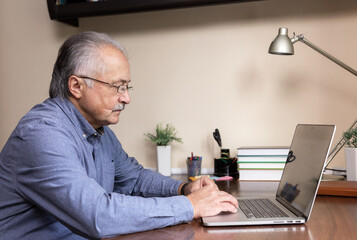 Senior man learn to use computer. Old man in glass and blue shirt using a laptop computer for...