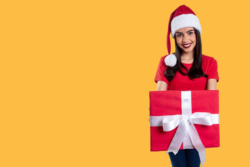 Woman with Christmas hat holding a gift, isolated on yellow background