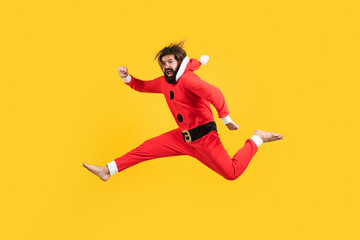 Fototapeta na wymiar Happy mature guy with Christmas costume jumping against the yellow background, xmas fun