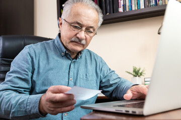 Senior man learn to use computer. Old man in glass and blue shirt using a laptop computer for online studying at home office