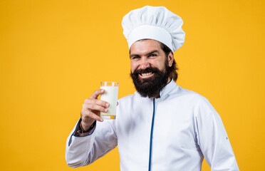 milkman with milk glass. male cook ready for preparing food. brutal hipster in apron going to be cooking meal. time for eating. happy baking. concept of housekeeping. mature bearded man wear chef hat