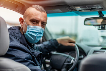man in a medical mask driving a car. The concept of second wave coronavirus, pandemic in quarantine...