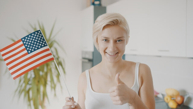 Young Blond Woman Holding USA Flag And Showing Thumbs Up. Election And Voting Rights. High Quality Photo